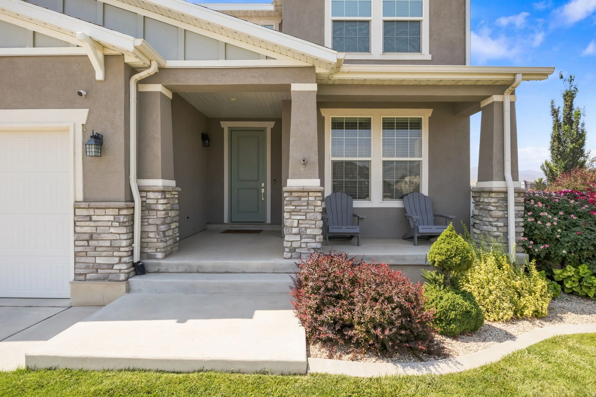 Stucco exterior with stone accents, a covered front porch, and a light-colored entry door