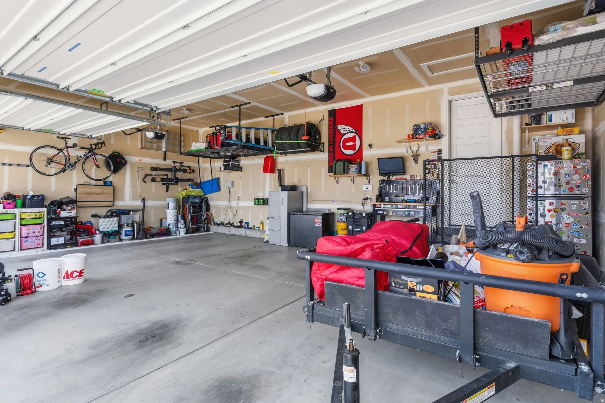 Large garage space featuring concrete flooring, an automatic garage door opener, and integrated overhead storage racks
