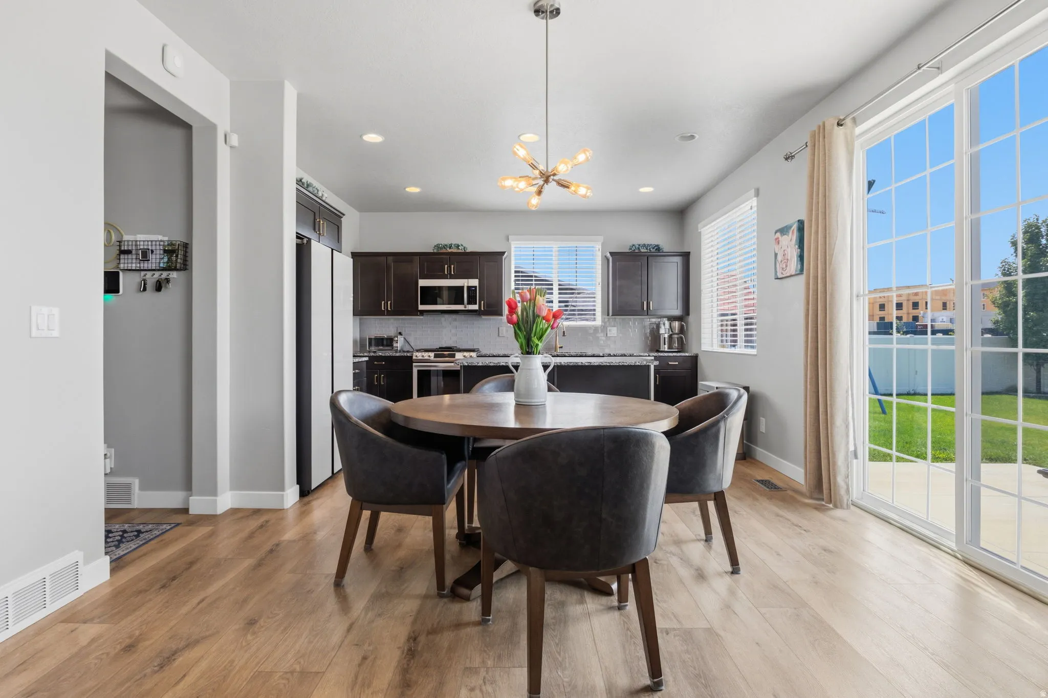 Kitchen and dining area featuring wood-finish flooring, dark wood cabinetry, stainless steel appliances, and a glass sliding door