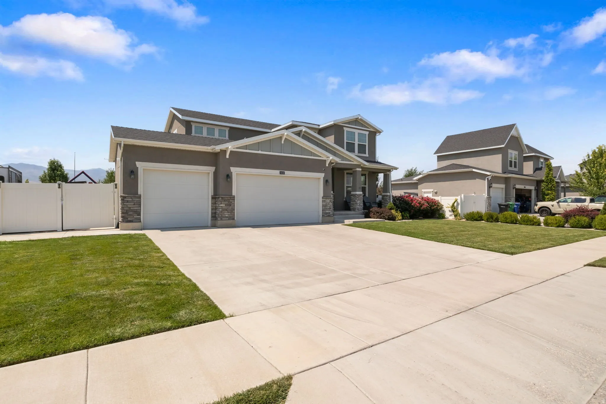 Contemporary stucco exterior with stone accents, a two-car garage, and a wide concrete driveway