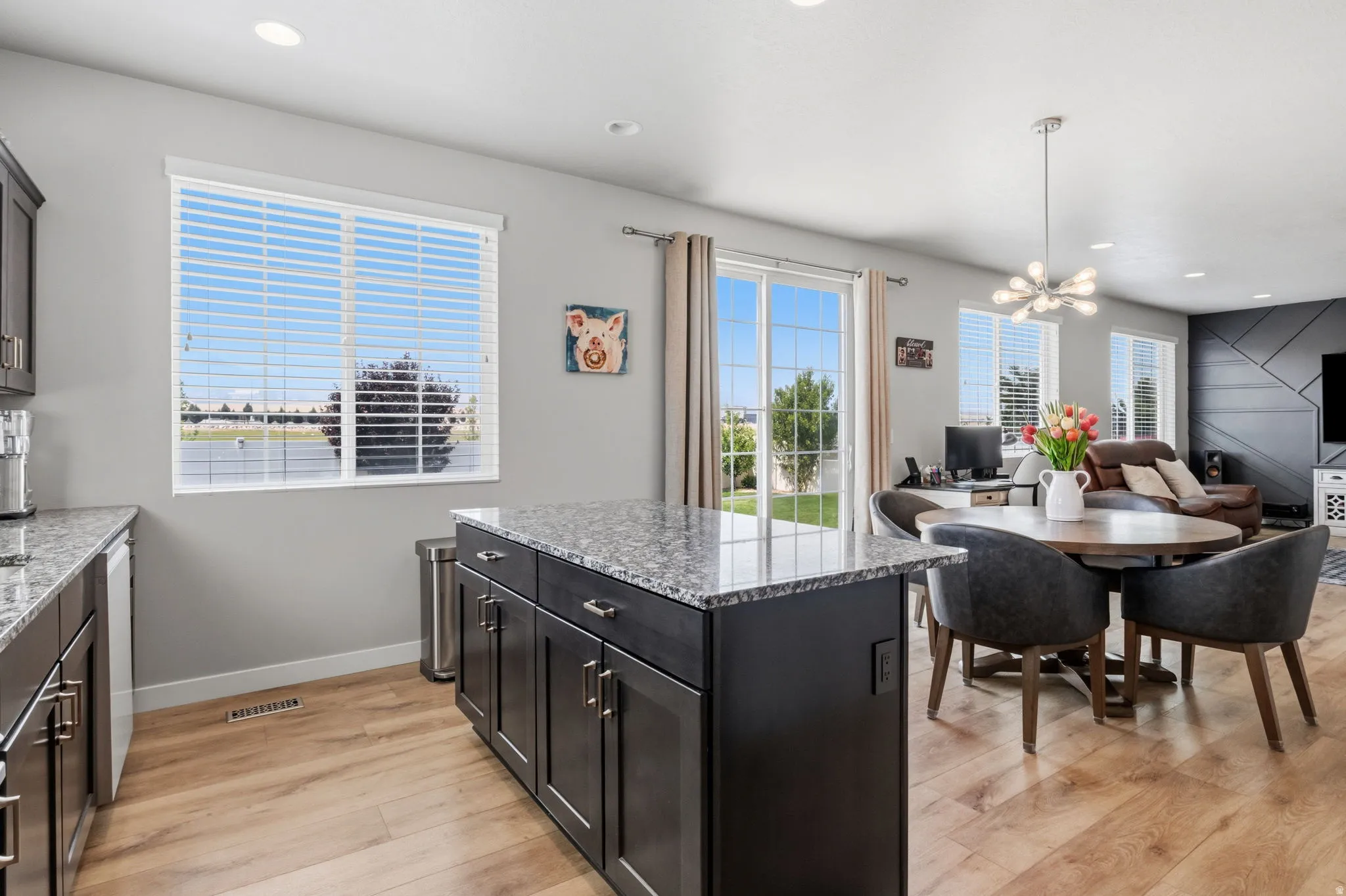 Open-concept living space featuring wood-finish flooring, dark cabinetry, and granite countertops
