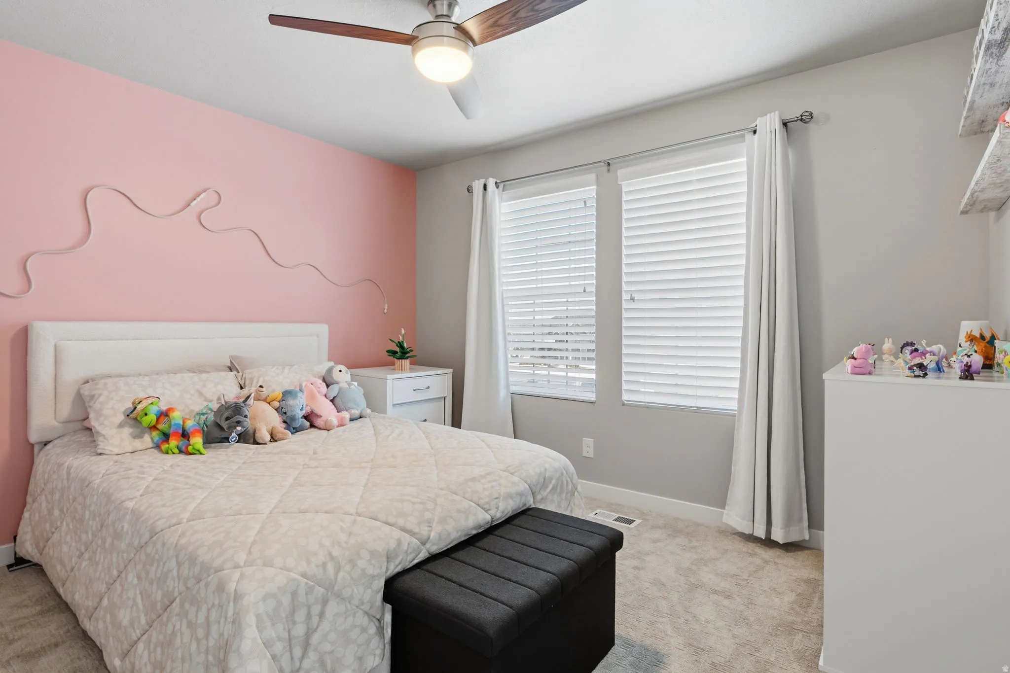 Ceiling fan with a light fixture, dual windows, blinds, and light-toned carpet flooring