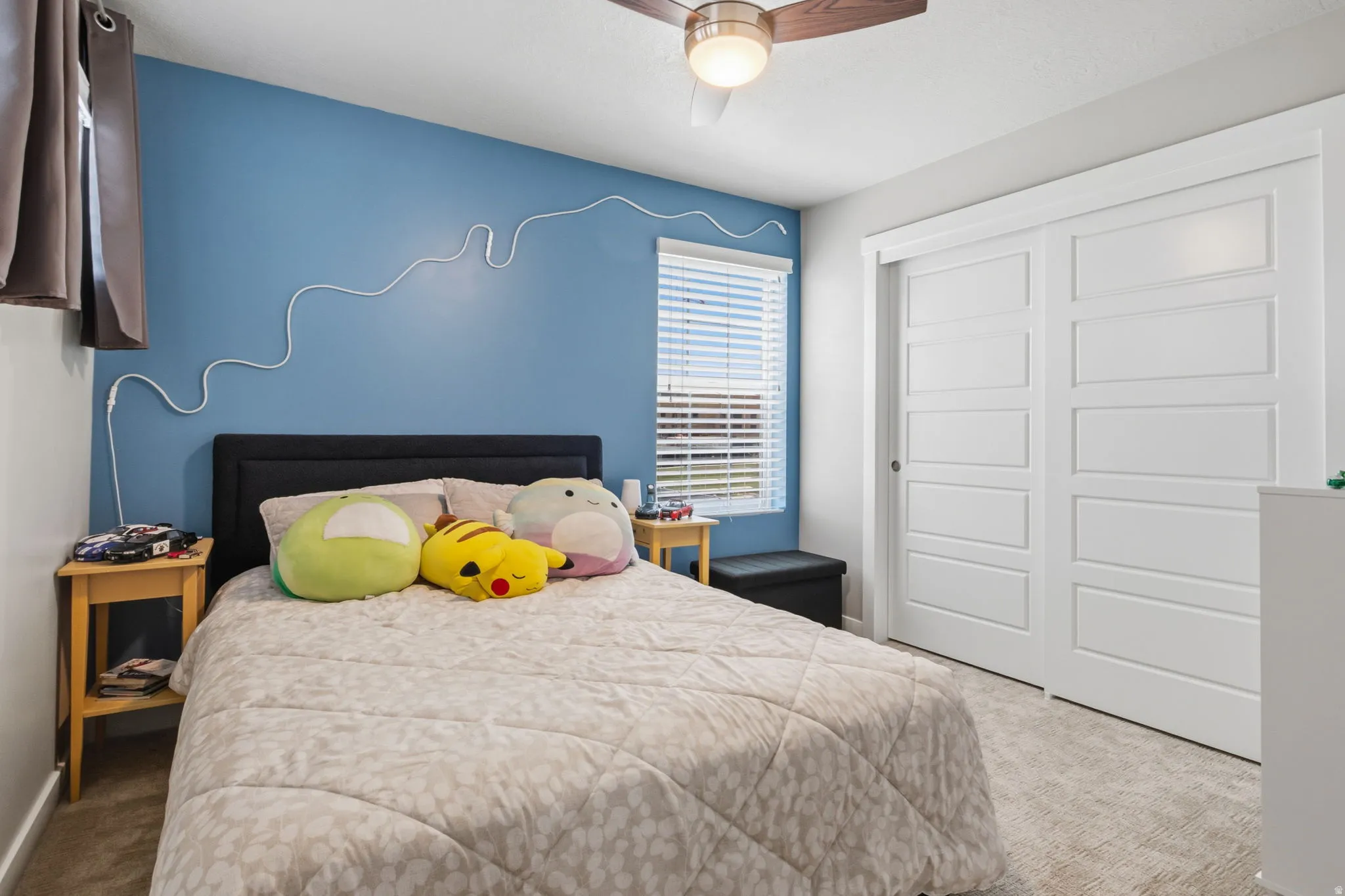 Ceiling fan with integrated lighting, window with blinds, two-panel sliding closet doors, and light-toned carpeting