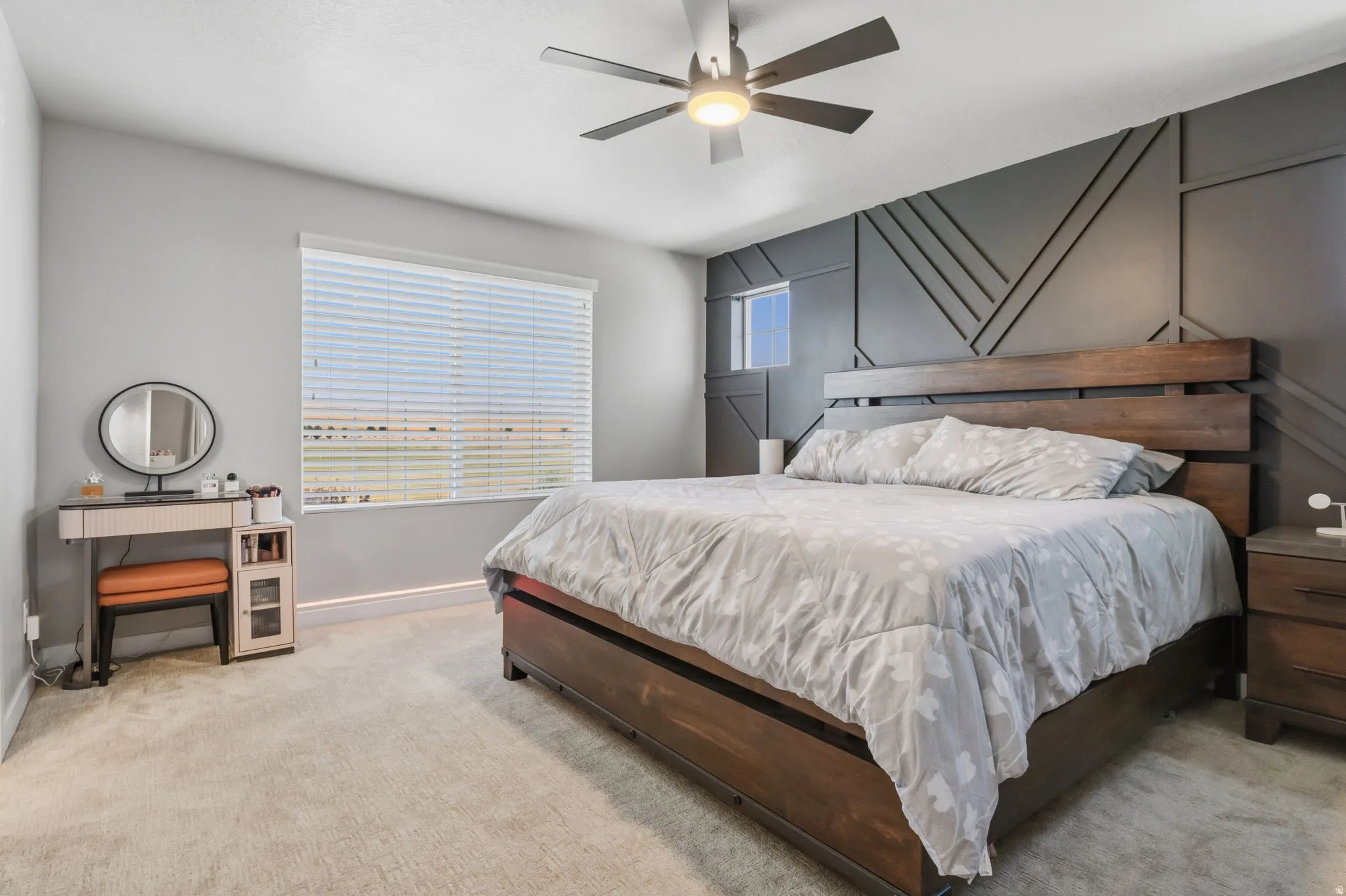 Spacious room featuring a decorative accent wall, a wide window with blinds, and ceiling fan with integrated lighting