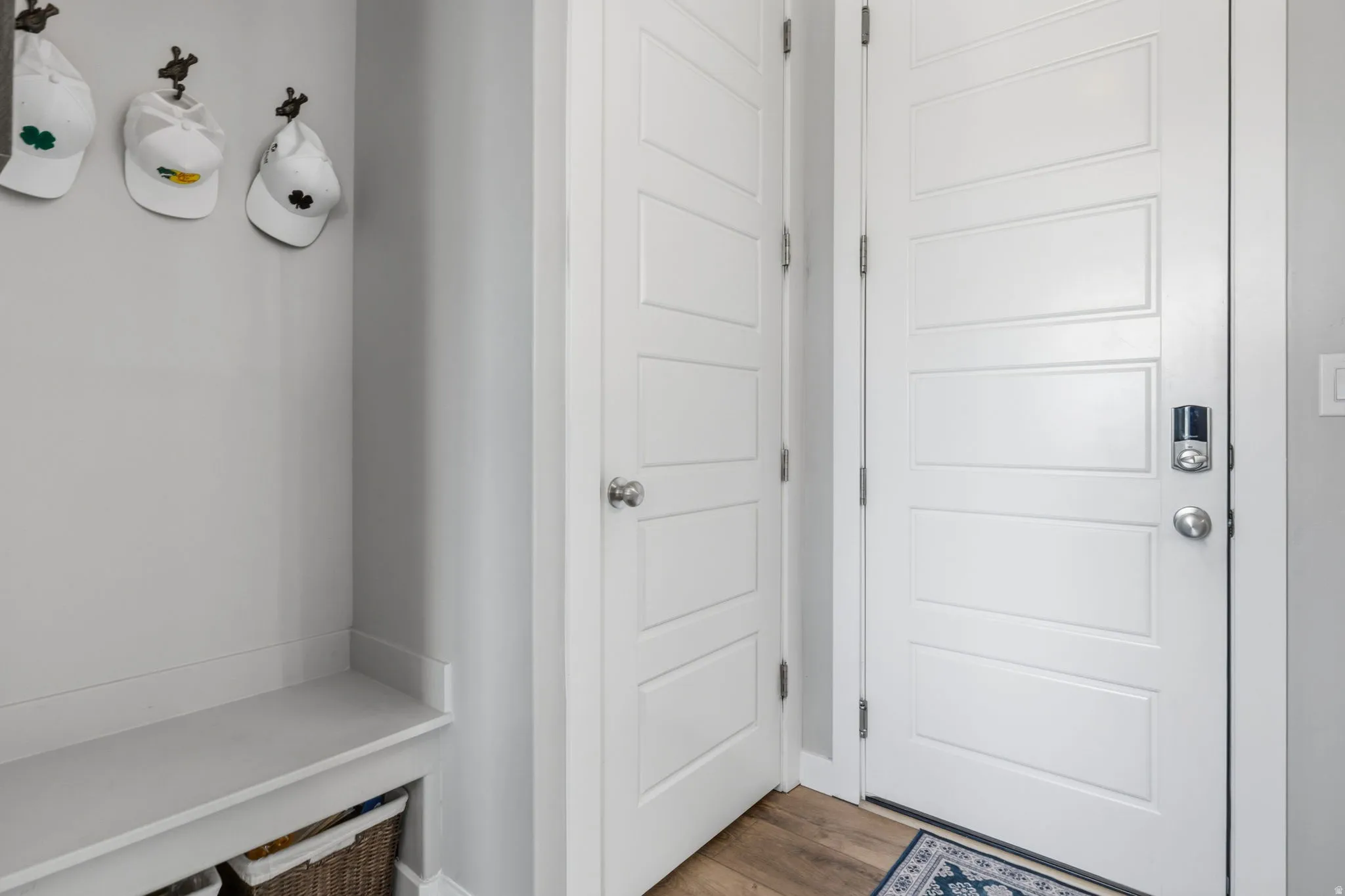 Built-in bench with storage, wood-finish flooring, white panel doors, and a keyless entry system