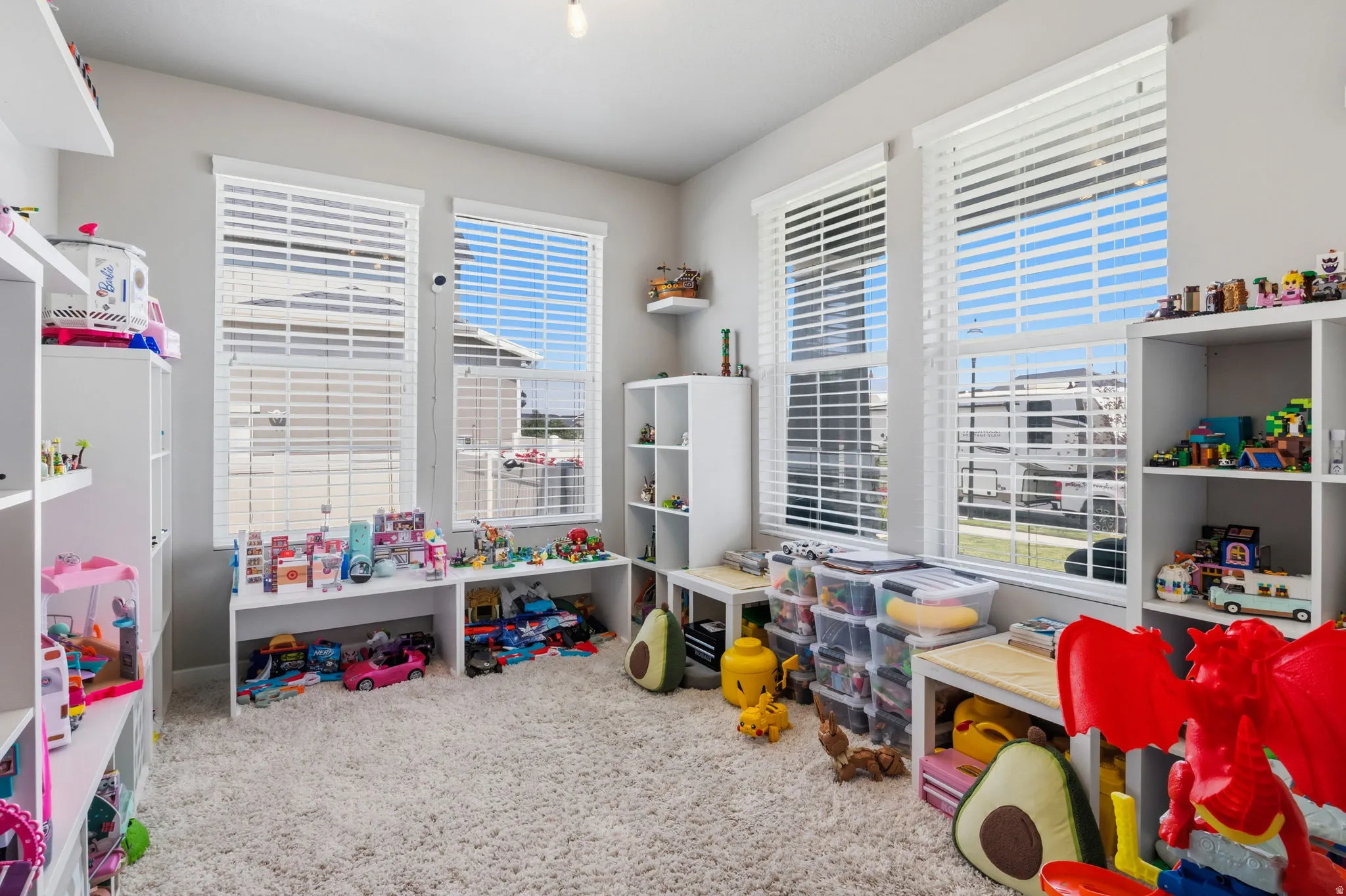 Textured carpeting, multiple white-framed windows with blinds, and light gray wall paint