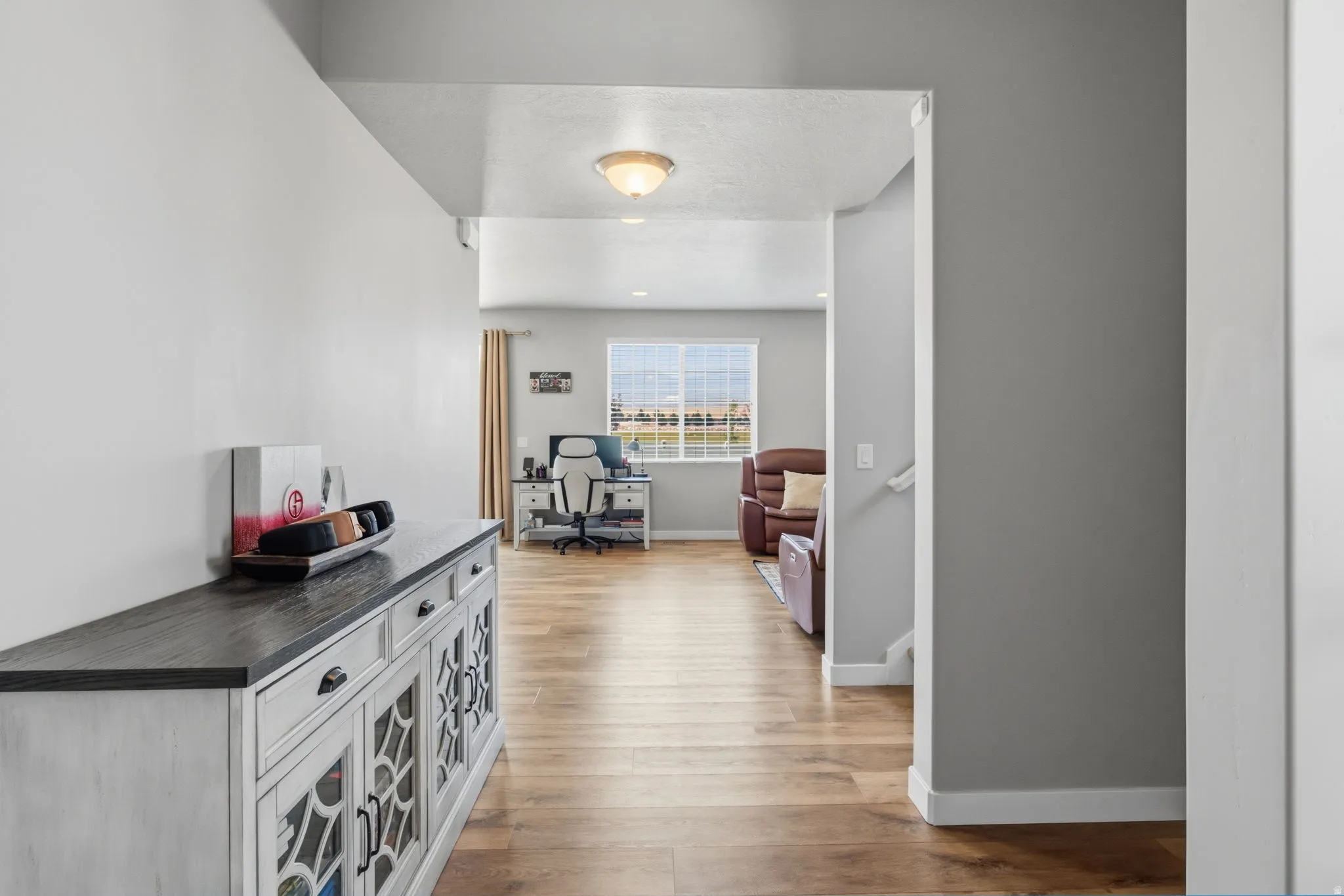 Wood-finish flooring throughout, light gray wall tones, and recessed lighting fixtures