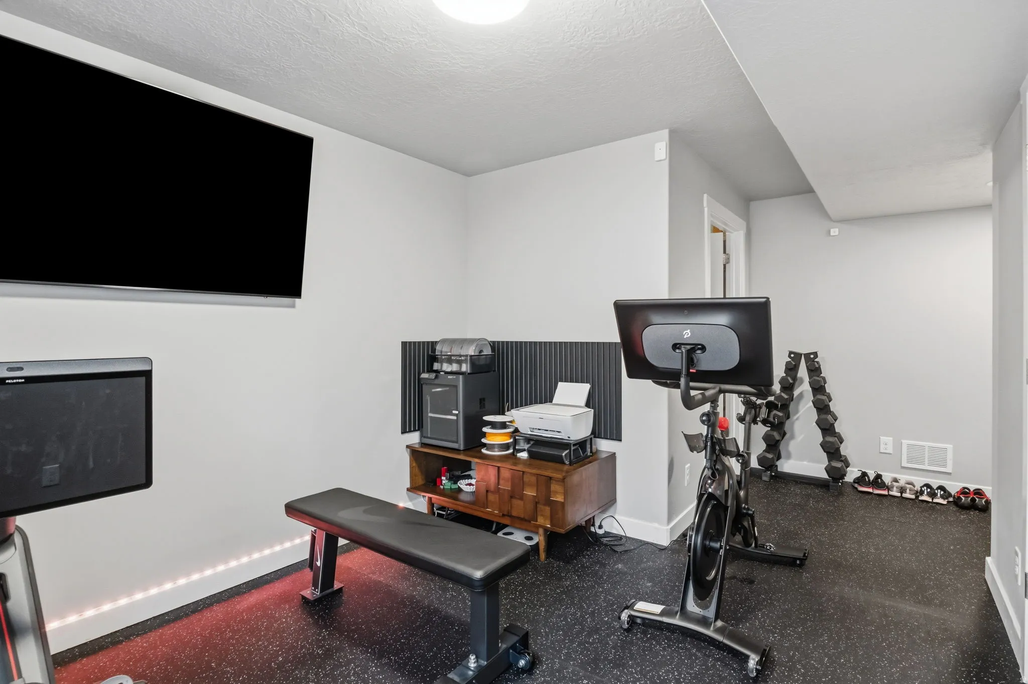 Wall-mounted television with integrated soundbar, recessed ceiling lighting, and rubberized flooring