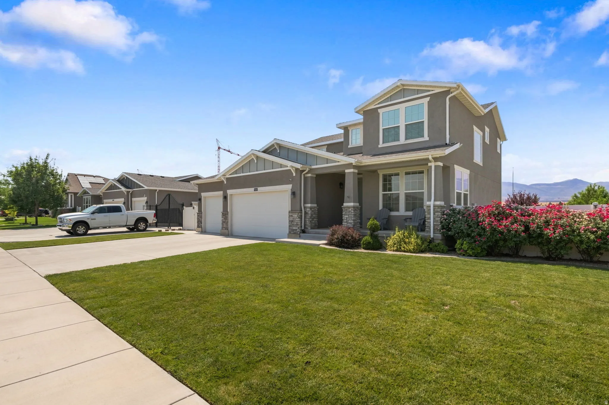 Two-story exterior with a two-car garage, stone accents, mature landscaping, and an inviting front porch