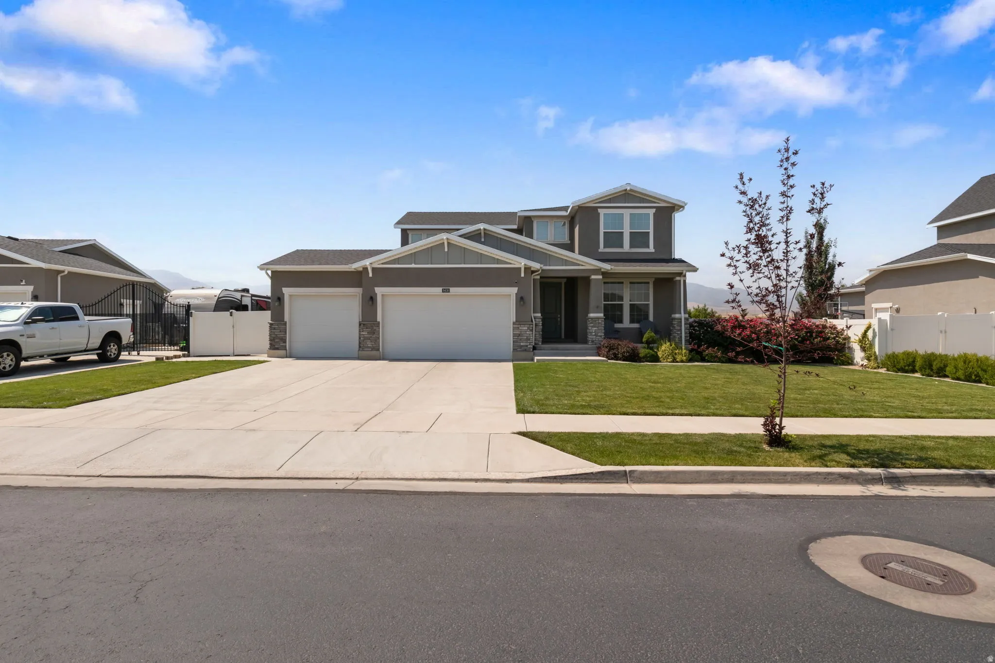 Two-story residence with a gray exterior, white trim, and stone accents