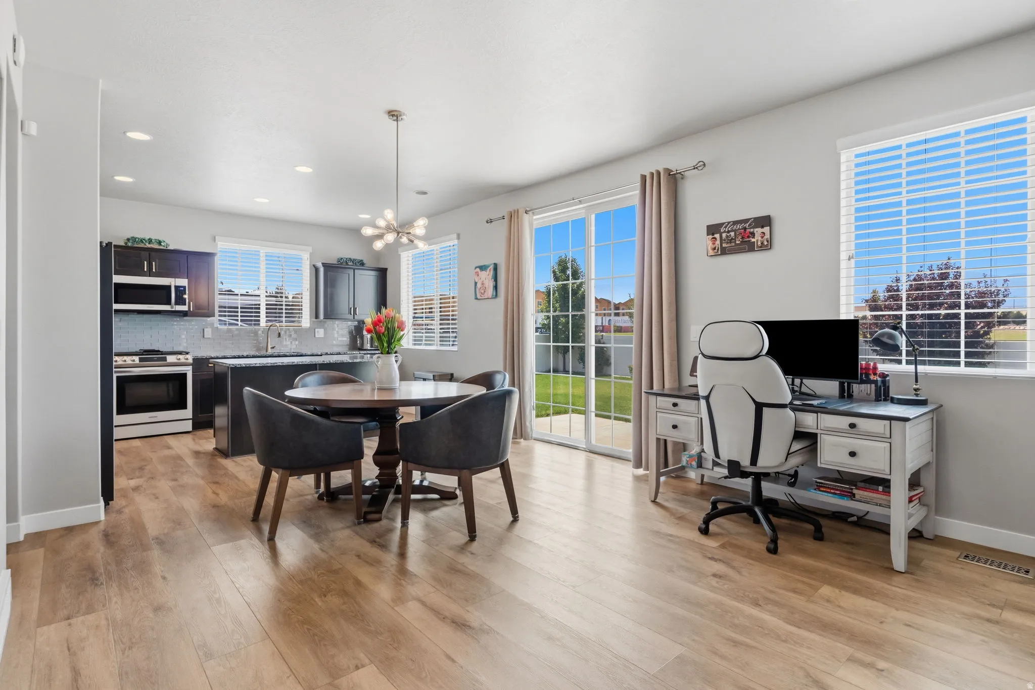 Open-concept living space featuring wood-finish flooring, recessed lighting, and a contemporary chandelier