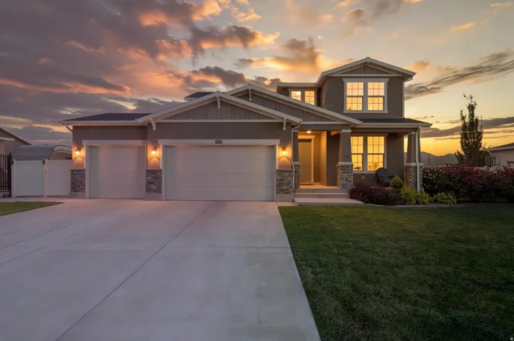 Contemporary exterior with stone accent columns, a two-car garage, and a covered porch entry