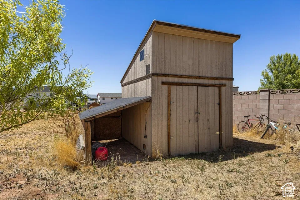 Two-story utility shed featuring a covered lean-to area, dual entry doors, and a sloped roof