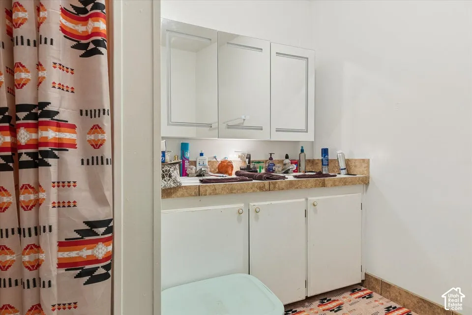 Bathroom vanity with white cabinetry, brown-toned countertop, and integrated sink