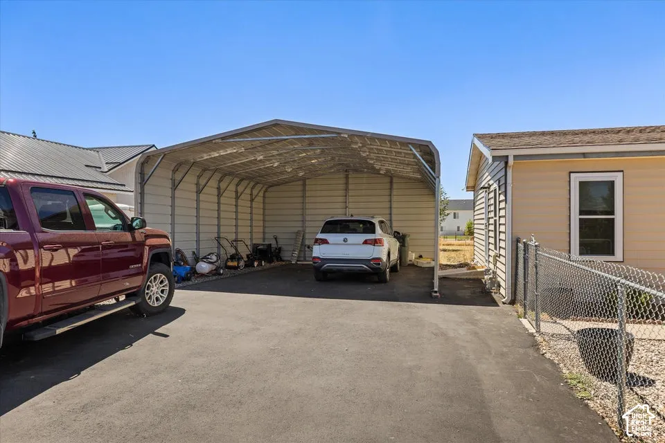 Paved driveway leading to a large metal carport structure, providing sheltered parking