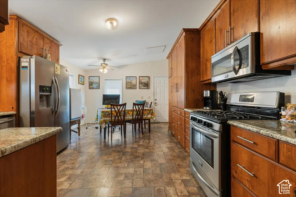 Full-height cabinetry, stainless steel appliances, granite countertops, tile-finish flooring, and a ceiling fan