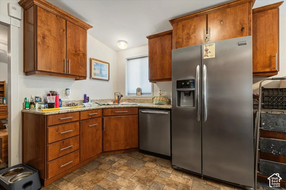 Kitchen featuring wood cabinetry, stainless steel appliances, a window with blinds, and durable tile flooring
