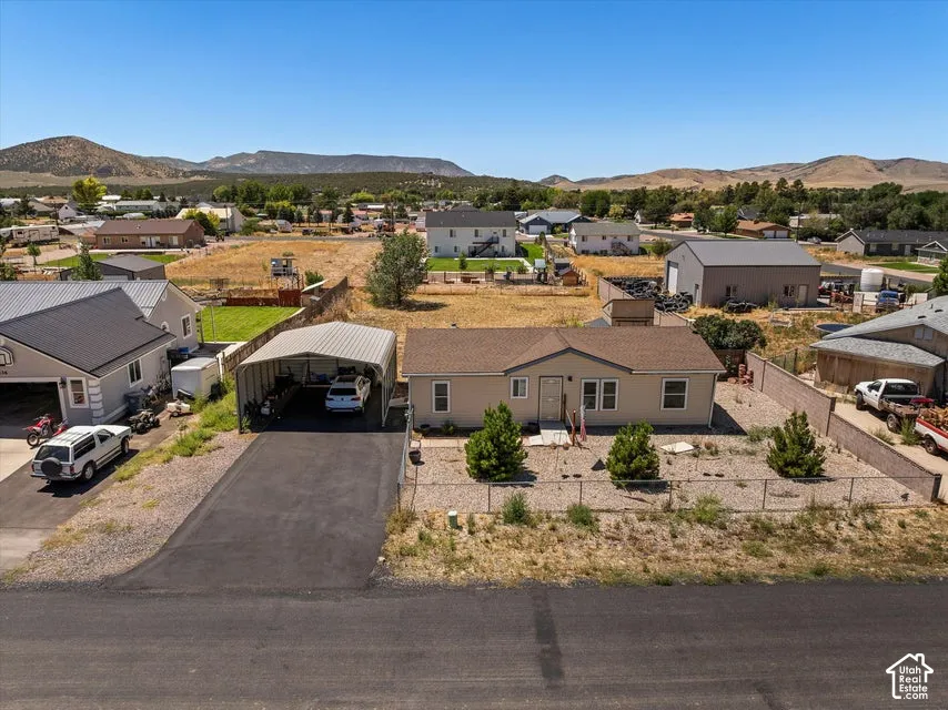 Single-story residence with a tan exterior, a paved driveway, and a covered carport structure