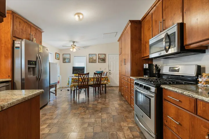 Full-height cabinetry, stainless steel appliances, granite countertops, tile-finish flooring, and a ceiling fan
