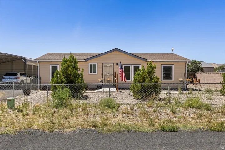Siding exterior with a covered carport, chain-link fencing, and a gravel front yard