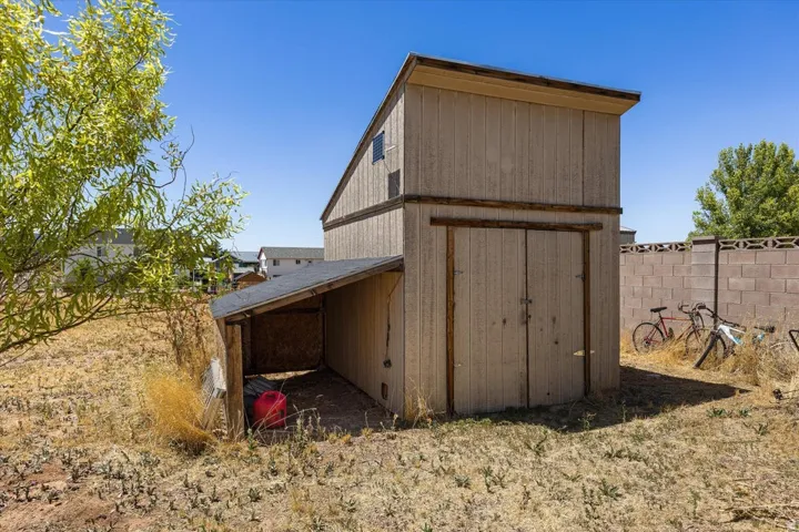 Two-story utility shed featuring a covered lean-to area, dual entry doors, and a sloped roof