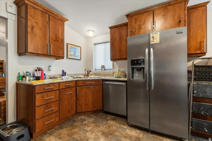 Kitchen featuring wood cabinetry, stainless steel appliances, a window with blinds, and durable tile flooring