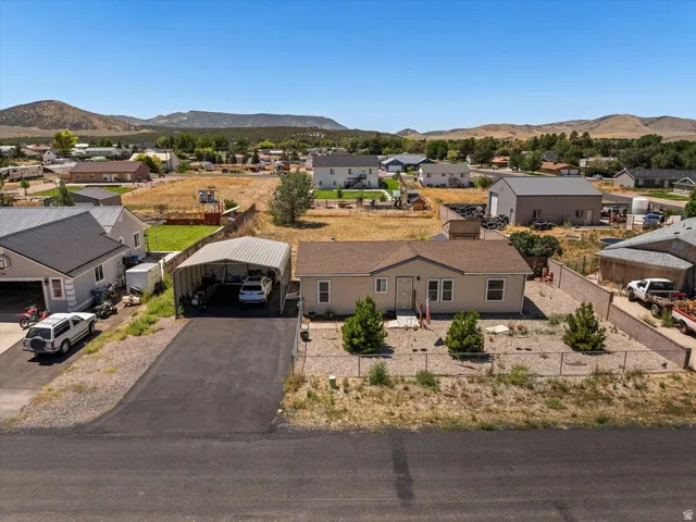 Single-story residence with a tan exterior, a paved driveway, and a covered carport structure