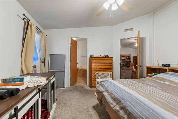 Carpeted bedroom with a ceiling fan, recessed window, and solid core doors