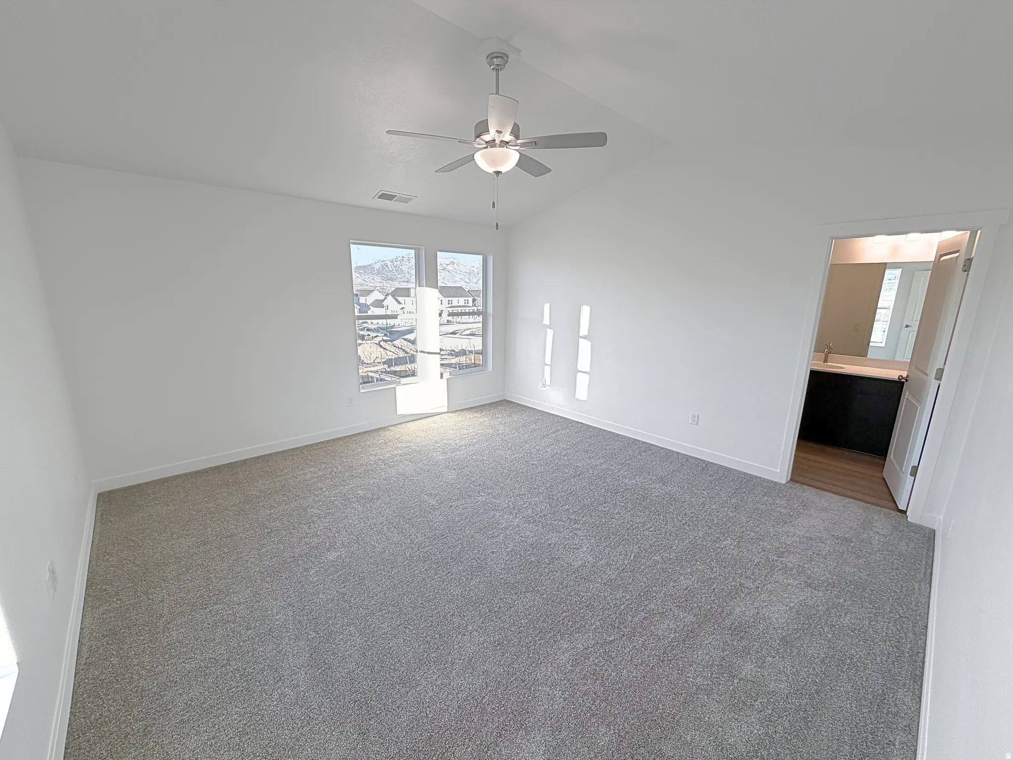 Spacious room featuring vaulted ceilings, recessed lighting, gray carpet, and two large windows