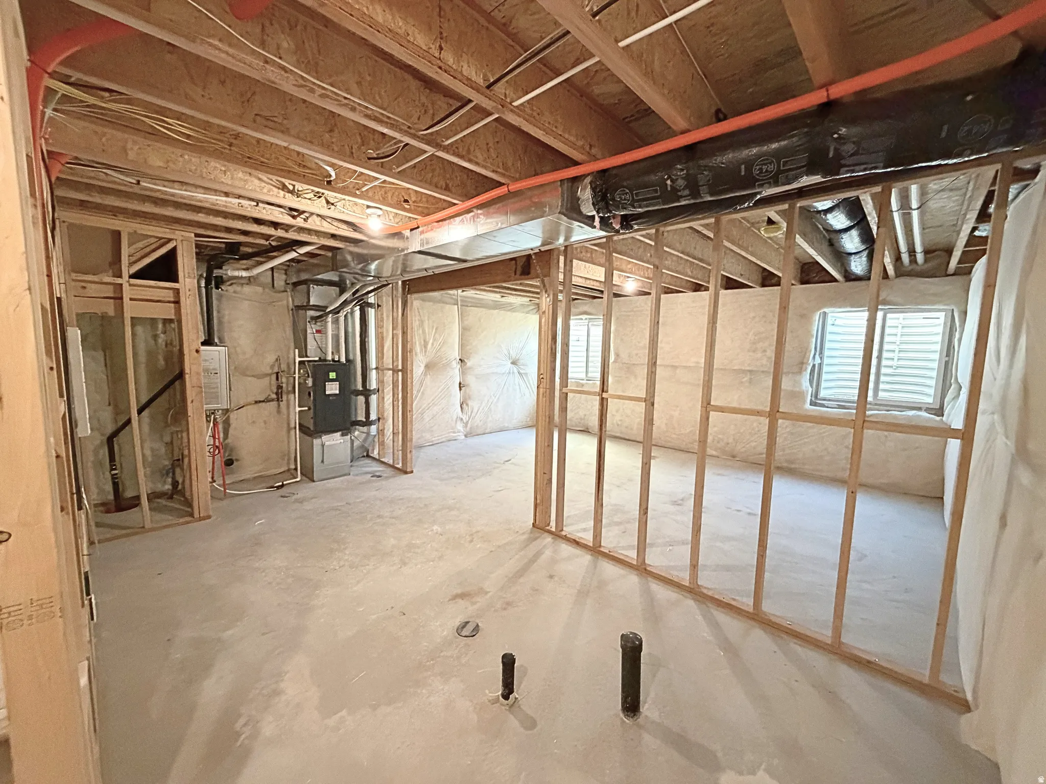 Unfinished basement with concrete flooring, framed interior walls, and exposed ceiling joists