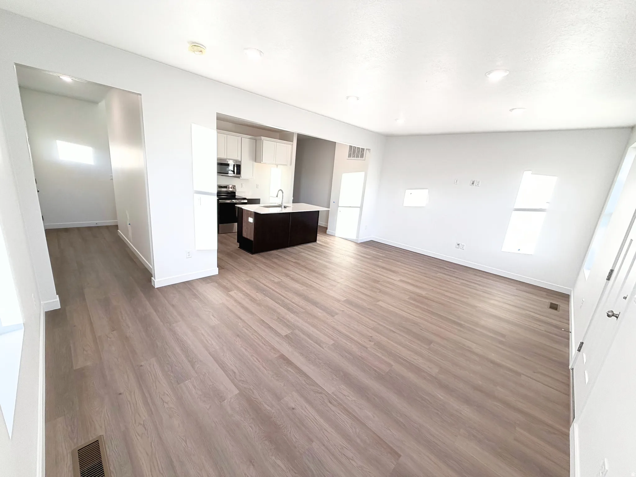 Expansive room featuring wood-finish flooring, white walls, and recessed lighting