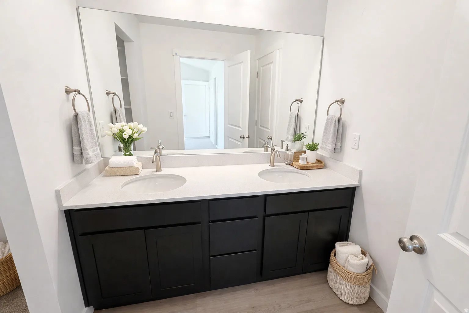 Dual under-mount sinks with brushed nickel fixtures, a light-toned countertop, dark wood-finish cabinetry, and a large wall-mounted mirror
