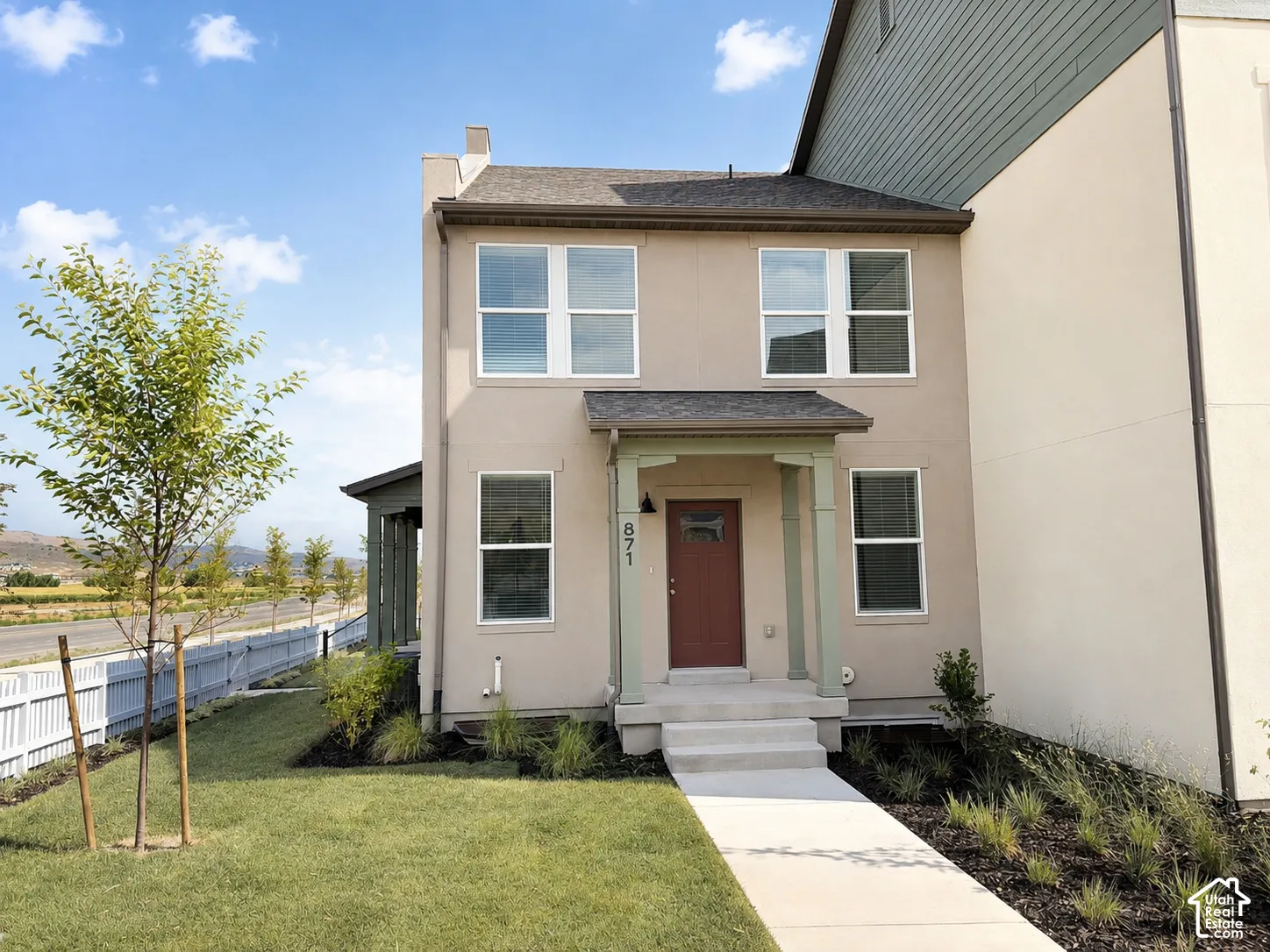 Stucco exterior with a covered porch, solid entry door, and multi-pane windows
