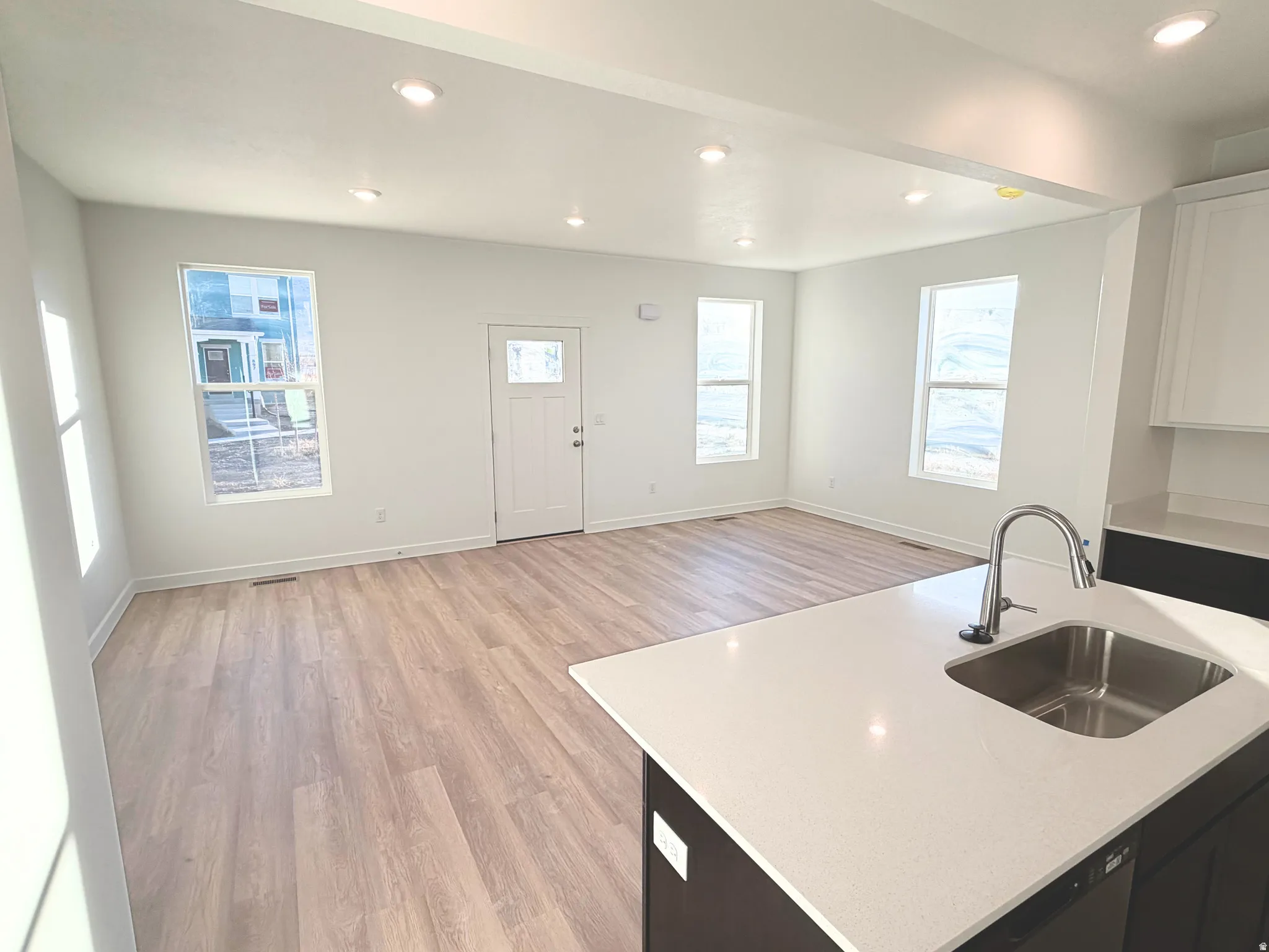 Open-concept living area with wood-finish flooring, recessed lighting, and multiple windows