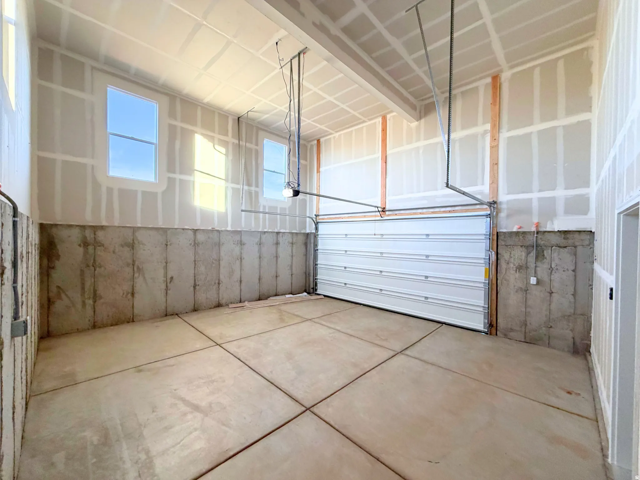 Expansive garage space with a concrete slab floor, high ceilings, and multiple windows providing natural light