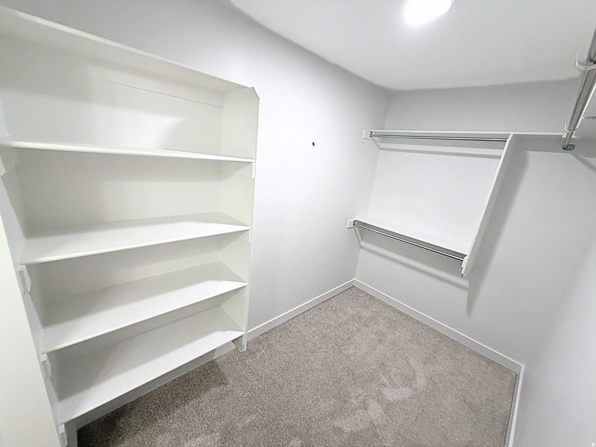 Walk-in closet featuring built-in shelving, dual hanging rods, and recessed lighting