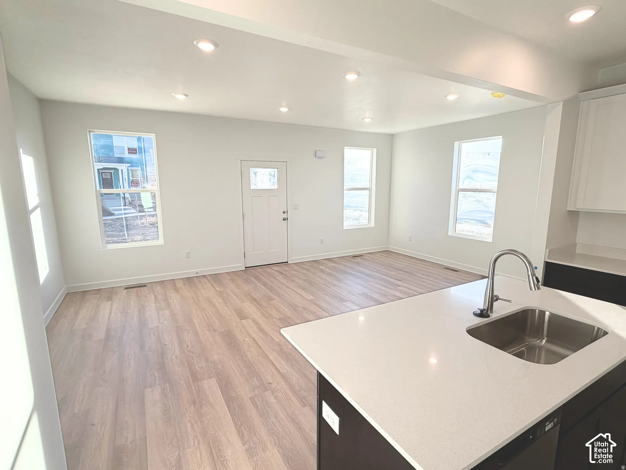 Open-concept living area with wood-finish flooring, recessed lighting, and multiple windows
