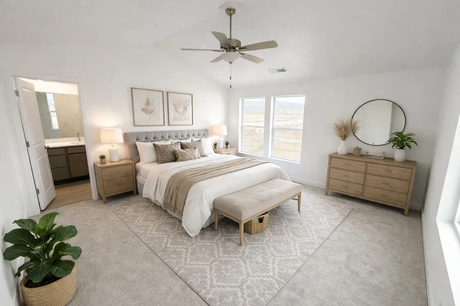 Vaulted ceiling with a ceiling fan, light-toned carpeting, multiple windows providing outdoor scenery, and an open doorway to a bathroom with a vanity