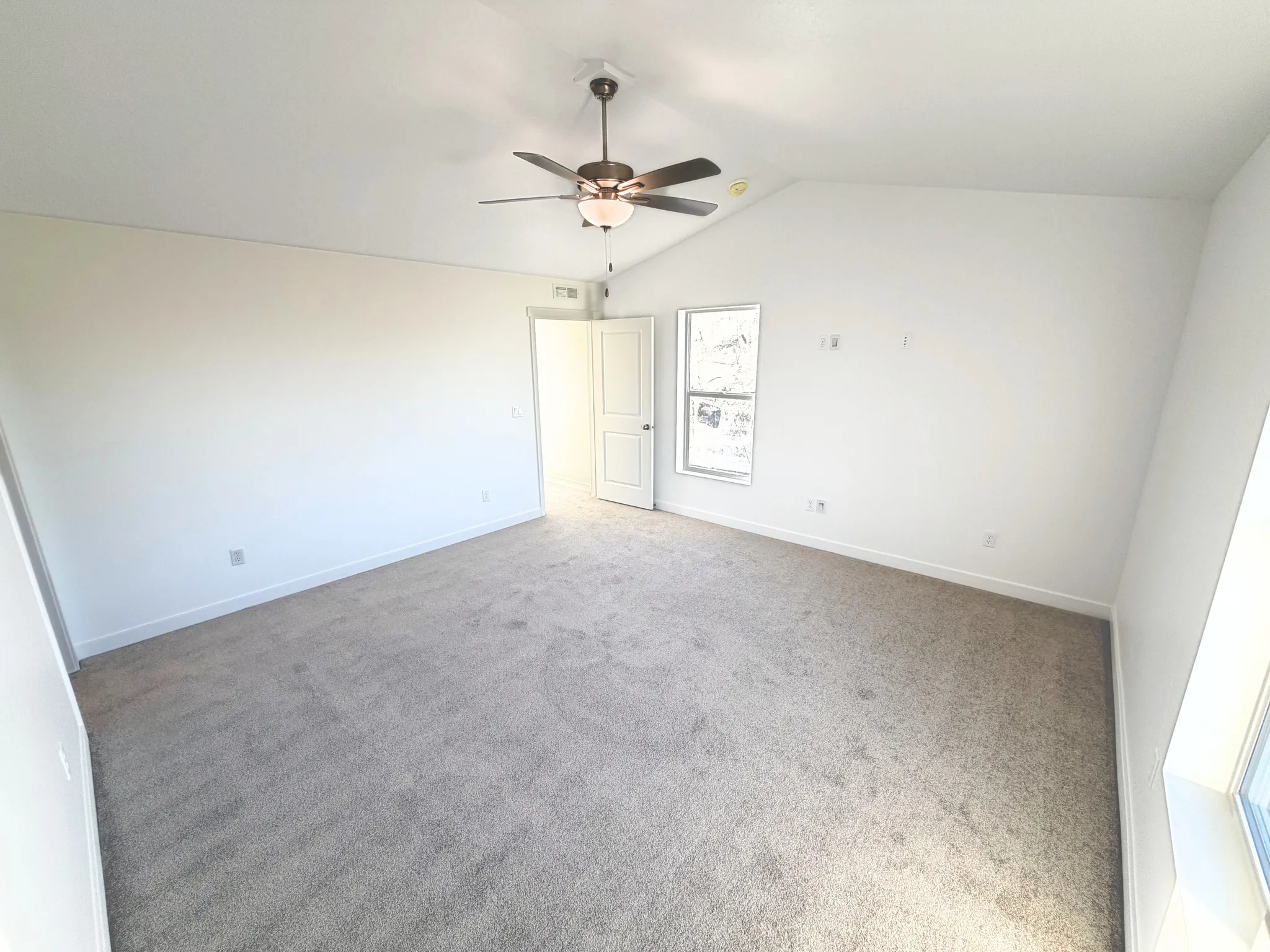 Vaulted ceiling, ceiling fan with integrated lighting, carpet flooring, and a single window