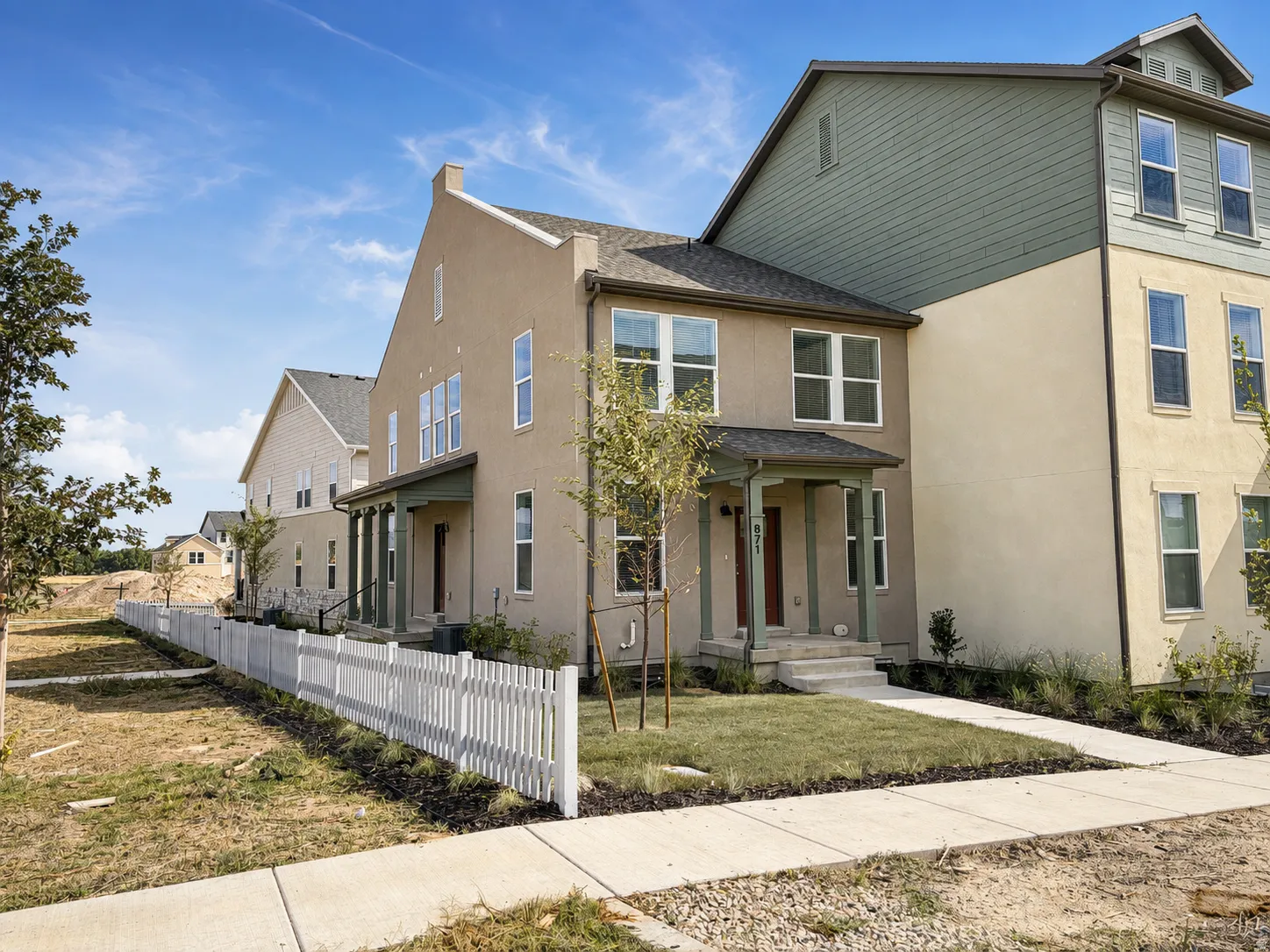 Stucco exterior with a covered front porch, white picket fence, and a concrete pathway
