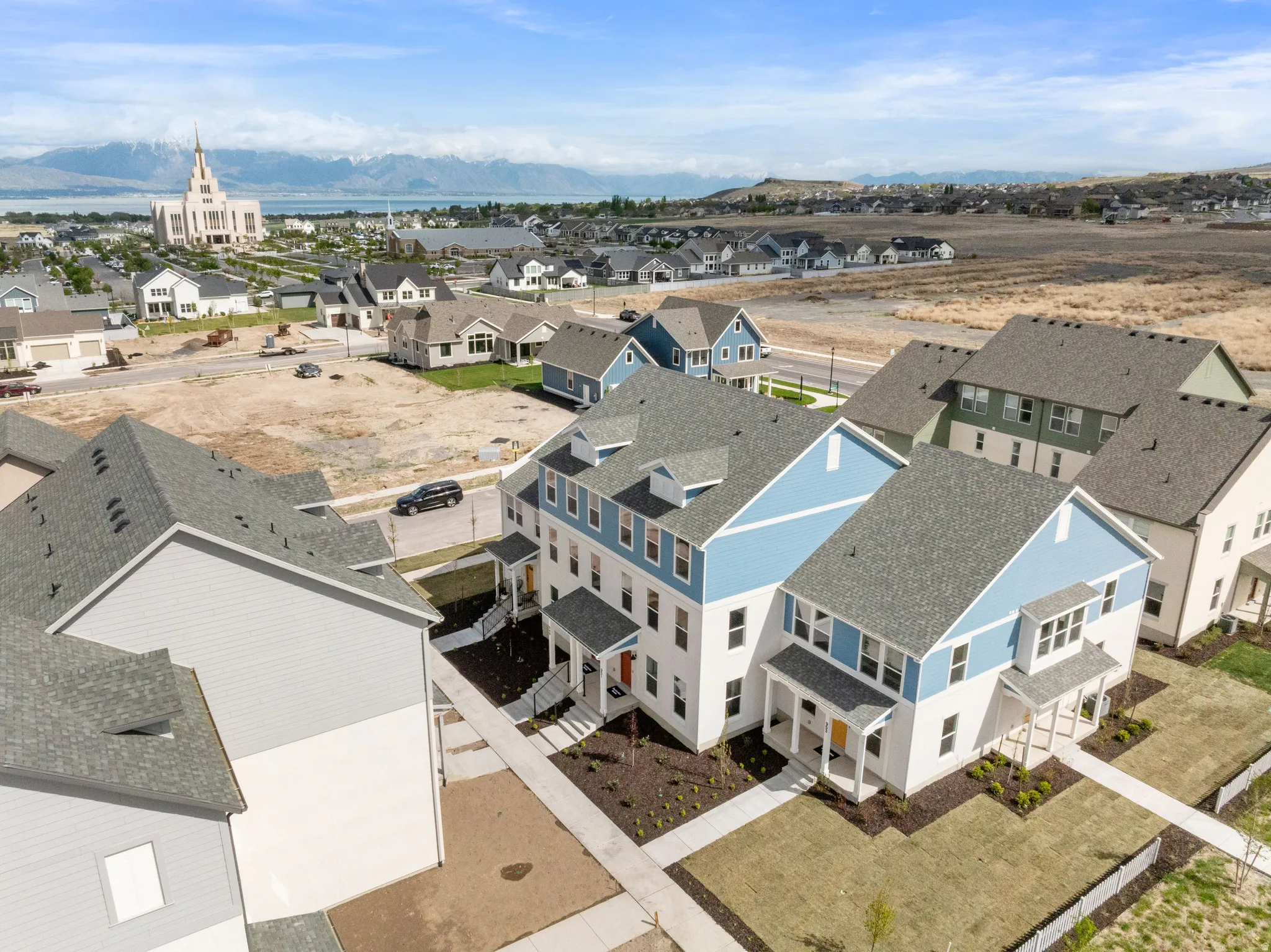 Newly constructed residential development featuring multiple townhome-style residences with covered entryways, landscaping, and paved pedestrian walkways