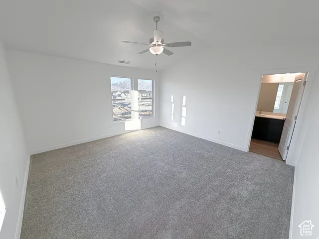 Spacious room featuring vaulted ceilings, recessed lighting, gray carpet, and two large windows