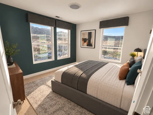 Room featuring a deep-hued accent wall, neutral carpeting, and multiple large windows with built-in fabric valances framing natural mountain scenery