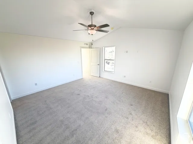 Vaulted ceiling, ceiling fan with integrated lighting, carpet flooring, and a single window
