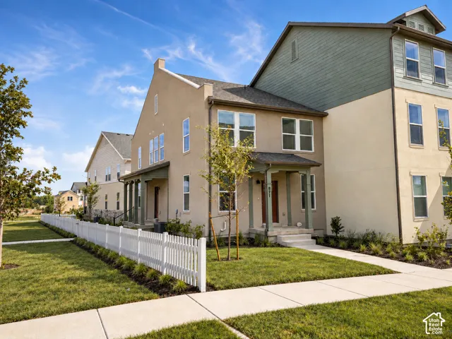 Multi-story residence featuring stucco and horizontal siding exterior, covered front porch, and white picket fencing
