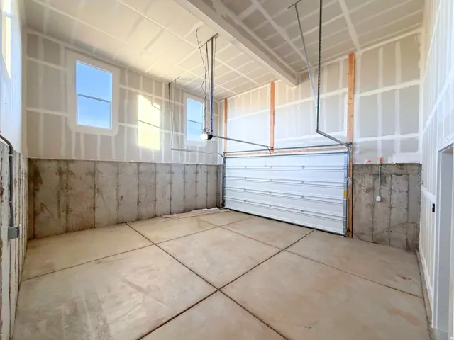 Expansive garage space with a concrete slab floor, high ceilings, and multiple windows providing natural light