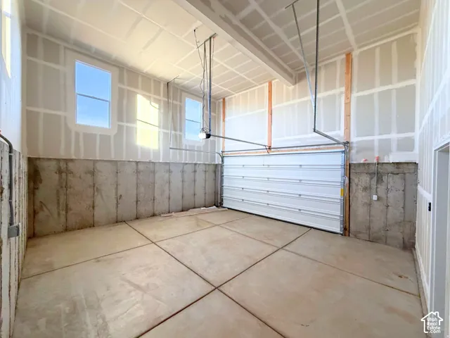 Expansive garage space with a concrete slab floor, high ceilings, and multiple windows providing natural light