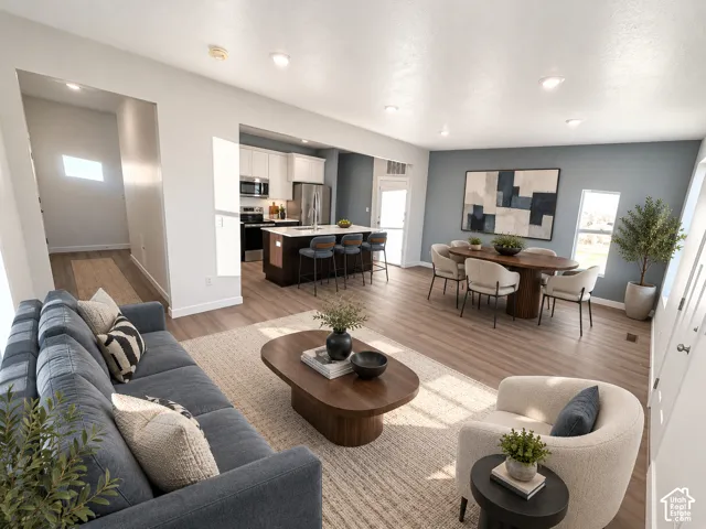 Open-concept living space featuring wood-finish flooring, recessed lighting, and a kitchen island with stone countertops