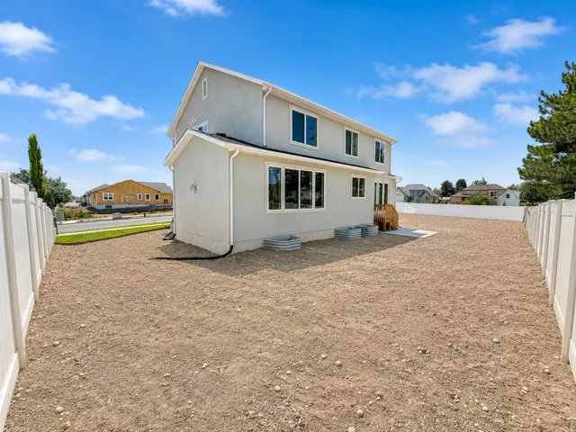 Expansive backyard featuring a privacy fence, concrete patio, and garden planters