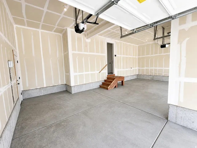 Spacious garage with concrete flooring, automatic garage doors, and unfinished drywall